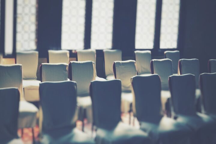 柔らかい光が差す部屋に並んだ空の椅子。説明会の会場のイメージ