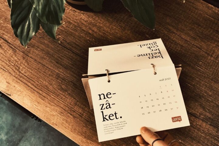 卓上のカレンダーに手で日付を書き込んでいるイメージ